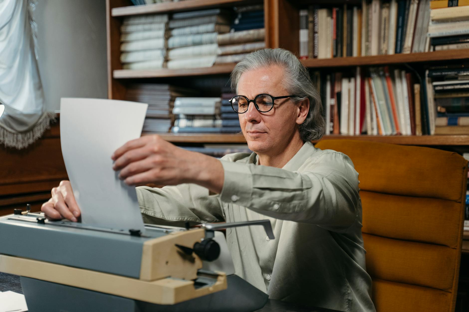 Author at a typewriter surrounded by bookshelves